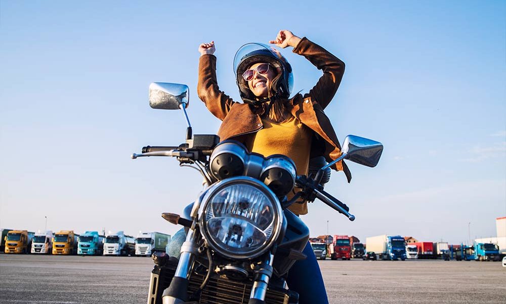 smiling-female-rider-sitting-her-motorcycle-with-arms-high-showing-happiness